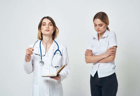 Nurse with documents in hands and woman patient on a light backgroundの写真素材