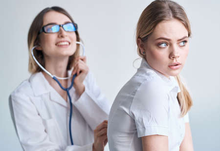 Happy woman doctor examine female patient in white t-shirt health modelの写真素材