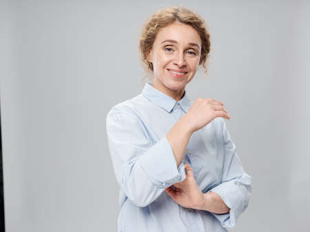 Elderly woman in a light shirt on a gray background smiling at the cameraの写真素材