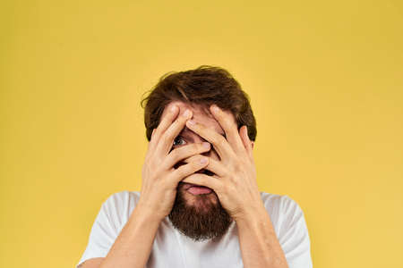 A man in a white t-shirt gestures with his hands lifestyle cropped view yellow background more funの写真素材