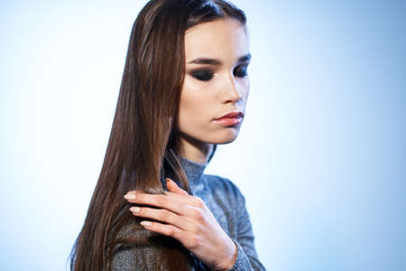 Pretty woman in gray sweater bright makeup long hair charm cropped viewの写真素材