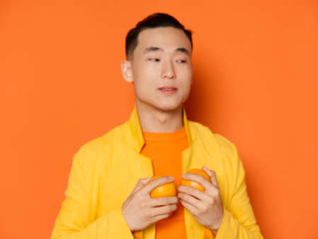 Asian guy with oranges in his hands on an isolated background