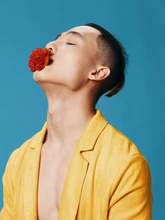 A handsome Asian man with a red flower in his mouth tilted his head back side view Copy Space close-upの写真素材