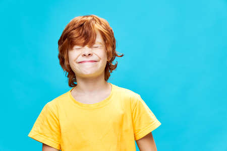Red-haired boy with closed eyes close-up yellow t-shirtの写真素材
