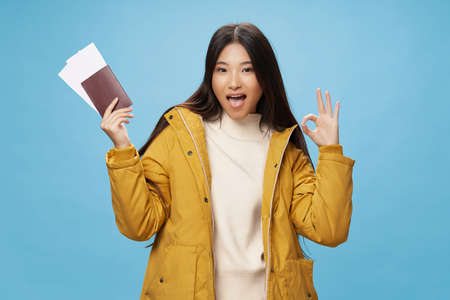 Woman holding passport and plane tickets vacation winter jacket travelの写真素材