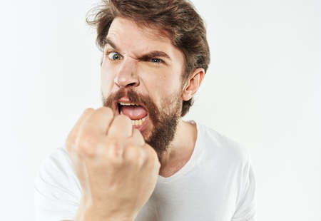 Angry man in a white t-shirt shows a fist gesturing with his hands to the modelの写真素材