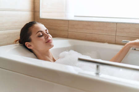 woman lies in the bathtub white foam relaxation clean skin