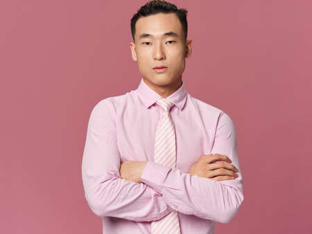 asian man tie shirt arms crossed before eating pink background cropped view modelの写真素材