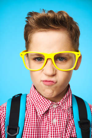 Schoolboy with a backpack wearing yellow glasses face close-up learningの写真素材