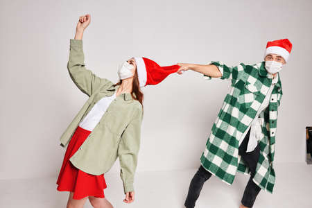 A man holds a woman by a hat Christmas holiday New Year medical maskの写真素材