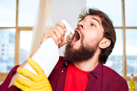 Cheerful man cleaning detergent homework hygiene interiorの写真素材