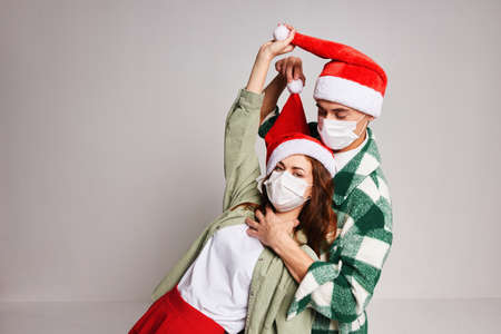 young couple santa hats holiday christmas medical mask studioの写真素材