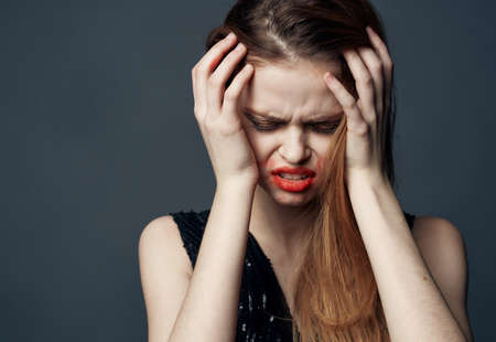 Woman in black dress touching face with hands and lipstick stress irritability
