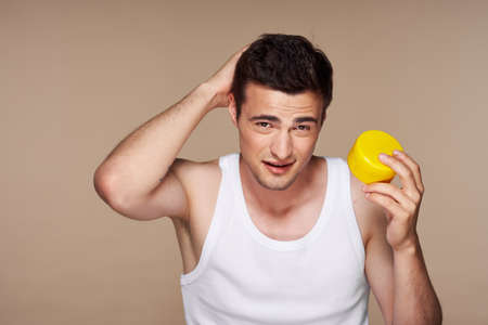 Man in a white vest skin care cream in the hands of a spa procedureの写真素材