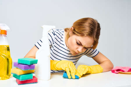 A cleaning lady sits at a table providing housekeeping services light background