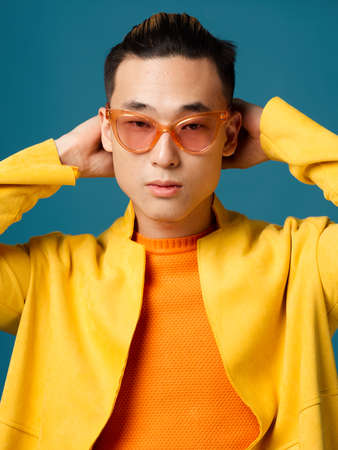 Asian man in jacket holds hands behind head cropped viewの写真素材