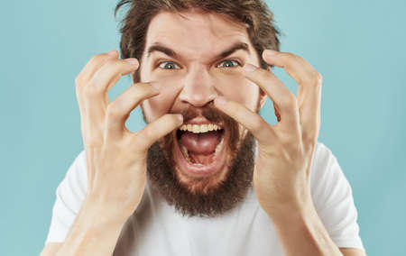 Bearded man emotions displeasure white t-shirt blue backgroundの写真素材