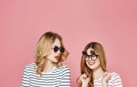 Cheerful girlfriends fashionable clothes communication friendship pink background
