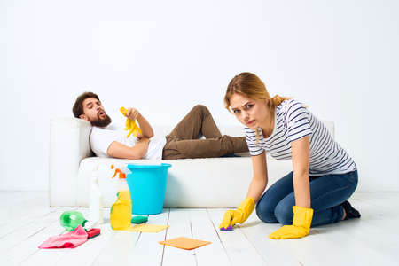 The man lies on the sofa woman washes the floors providing services interior housework