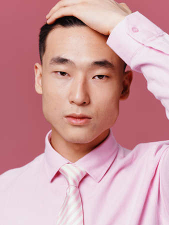 Handsome man of Asian appearance hand on head pink shirt close-upの写真素材