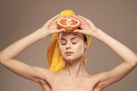 Woman with grapefruit in her hand clean skin bare shoulders spa health treatments