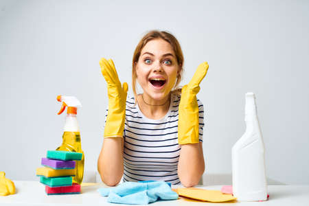 woman sitting at the table detergent rags sponges home care interior light backgroundの写真素材