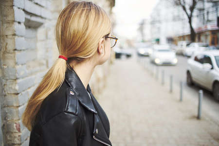 woman walking down the street near the building in leather jacket cropped viewの写真素材