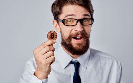 man with a coin in his hand success joy cryptocurrency Bitcoin gray background
