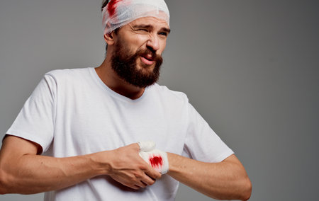 a man in intensive care bandaged head blood on his arm concussionの写真素材