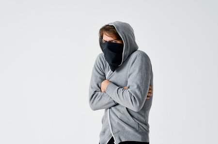 male hacker in a black mask and in a hood on a light background theft theftの写真素材