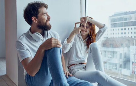 cheerful young couple sitting near the window technology communication interiorの写真素材