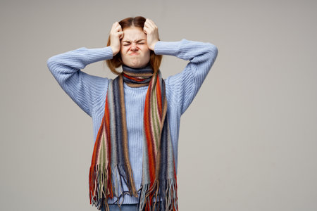 woman touching her head with her hands health problems warm clothes scarf headacheの写真素材