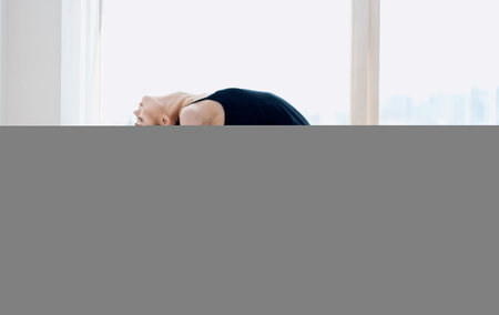 Woman in dark clothes doing yoga indoors slim figure asana sportの写真素材