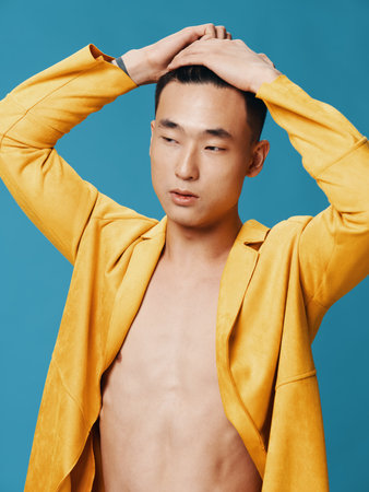 handsome guy in yellow jacket on naked torso and blue background modelの写真素材