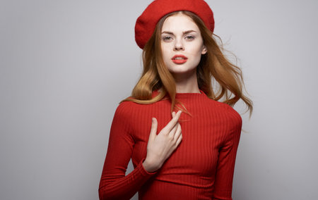 Beautiful woman in red sweater and hat cosmetics model gray backgroundの写真素材