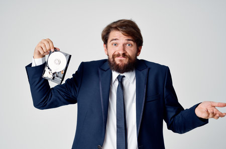 emotional business man in a suit gesturing with his hands and disassembled hard driveの写真素材