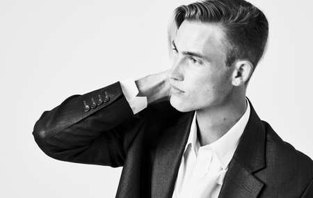 Handsome young man holds his hand near his face on a light background cropped view of a suitの写真素材