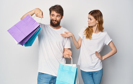 Happy young couple in white T-shirts with packages in hands Shopping is joyの写真素材