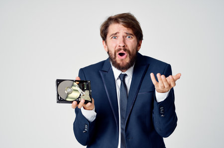 emotional business man in a suit gesturing with his hands and disassembled hard drive