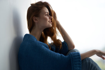 pretty woman covered with a blanket sits at home near window weekendの写真素材