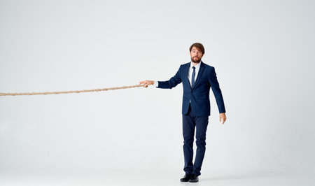 business man in a suit pulls a rope on a light backgroundの写真素材
