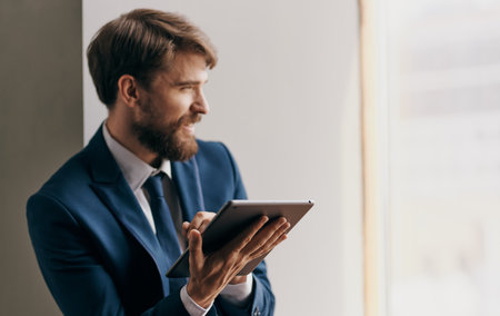 man in suit near the window tablet in the hands of technology Professional businessmanの写真素材