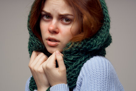 women in a knitted headdress and in a blue sweater on a gray background health problems runny noseの写真素材