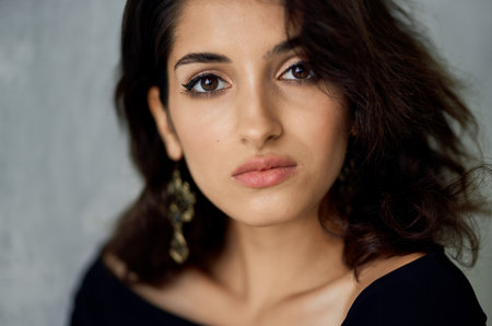 portrait of a beautiful romantic woman in earrings and in an evening dress makeup model gray...