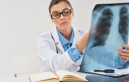 A nurse in a medical gown with an X-ray sits at a table in the office