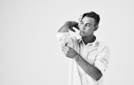 A young man in a shirt and trousers on a light background touches his head with his hands cropped viewの写真素材