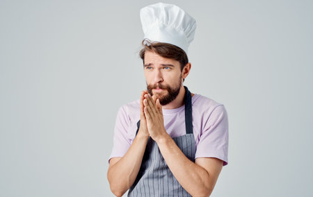 The cook in a gray mess and in a pink shirt is gesturing with his hands of emotionの写真素材