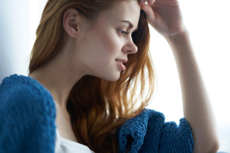 pretty woman in blue plaid sits on the windowsill home interior charmの写真素材