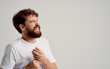 a man touches his wrists on a light background and a white t-shirtの写真素材