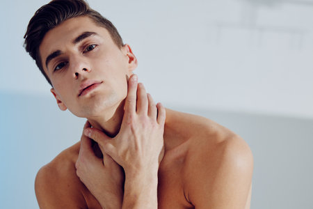 Portrait of a young man who touches his neck with a naked torsoの写真素材